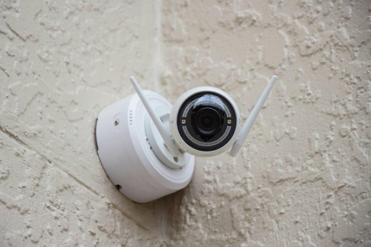 Image of a smart lock installed on a front door alongside a motion camera mounted nearby.