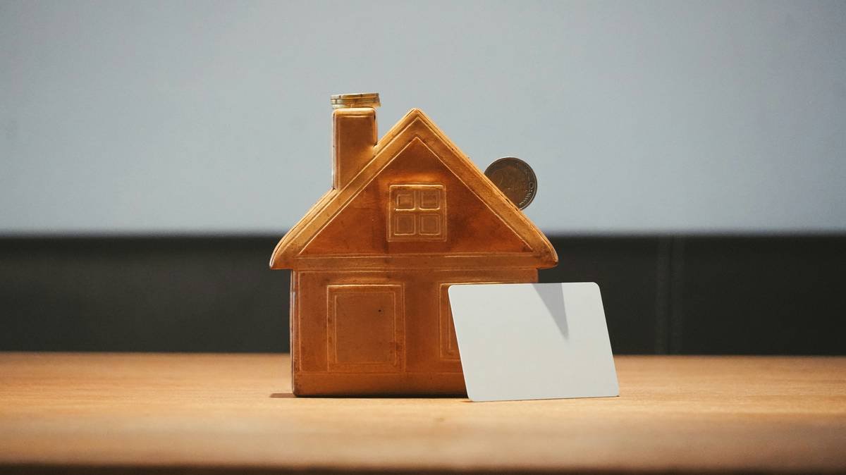 A small house bank with a coin and blank card.