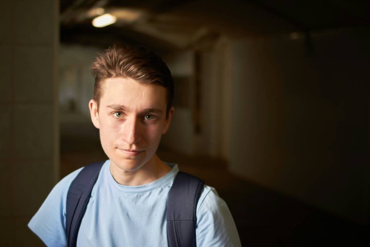 Young man stands in a dark corridor.